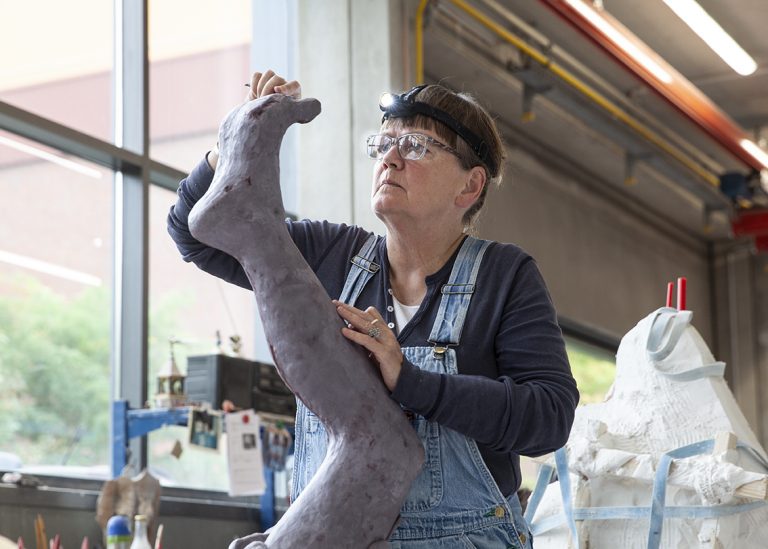 En kvinna skulpterar ett ben.