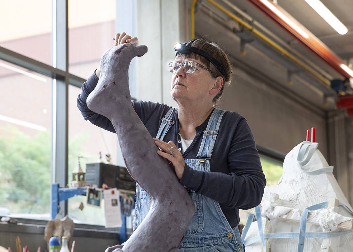 En kvinna skulpterar ett ben.