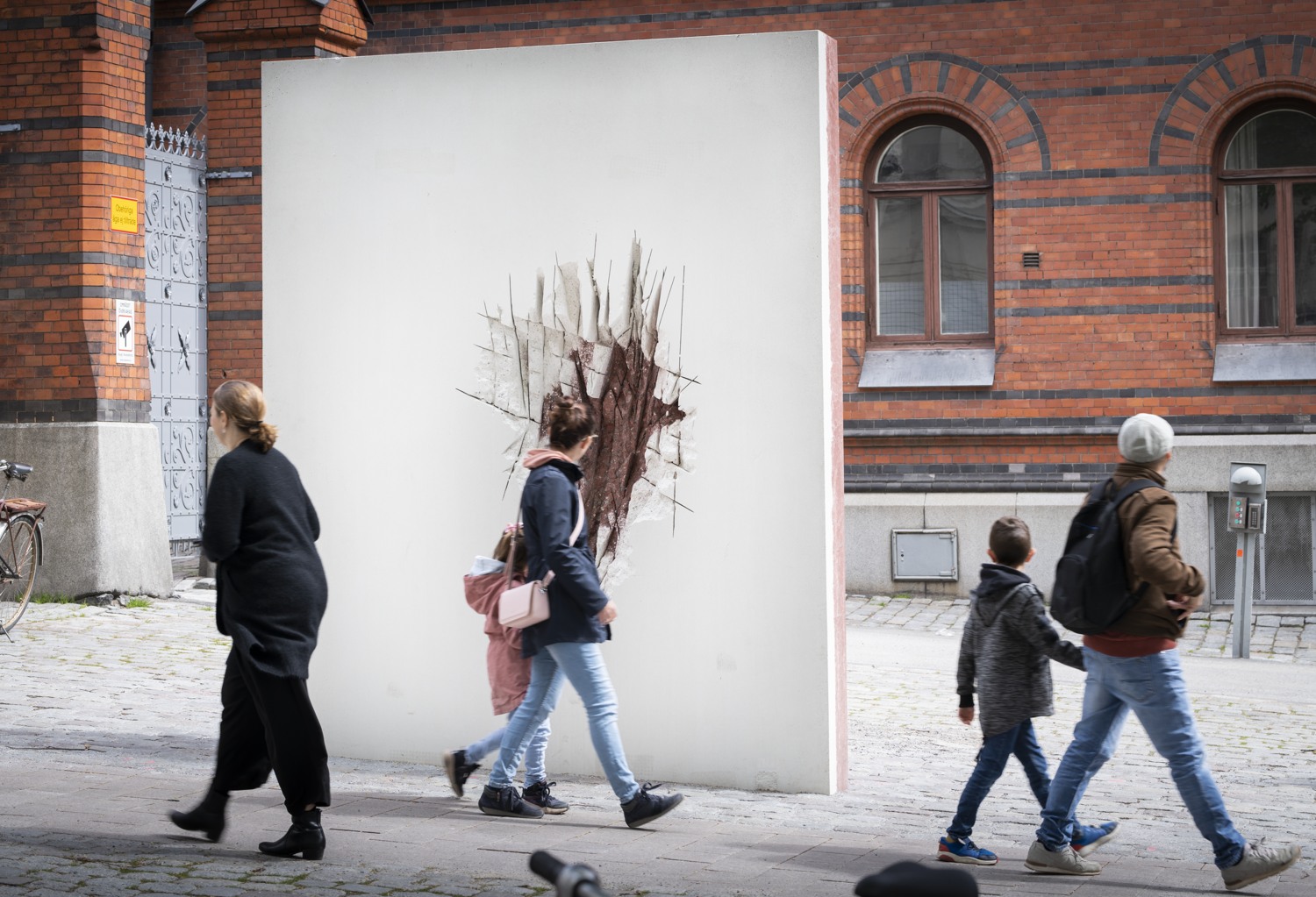 Människor passerar verket och vänder sig om.