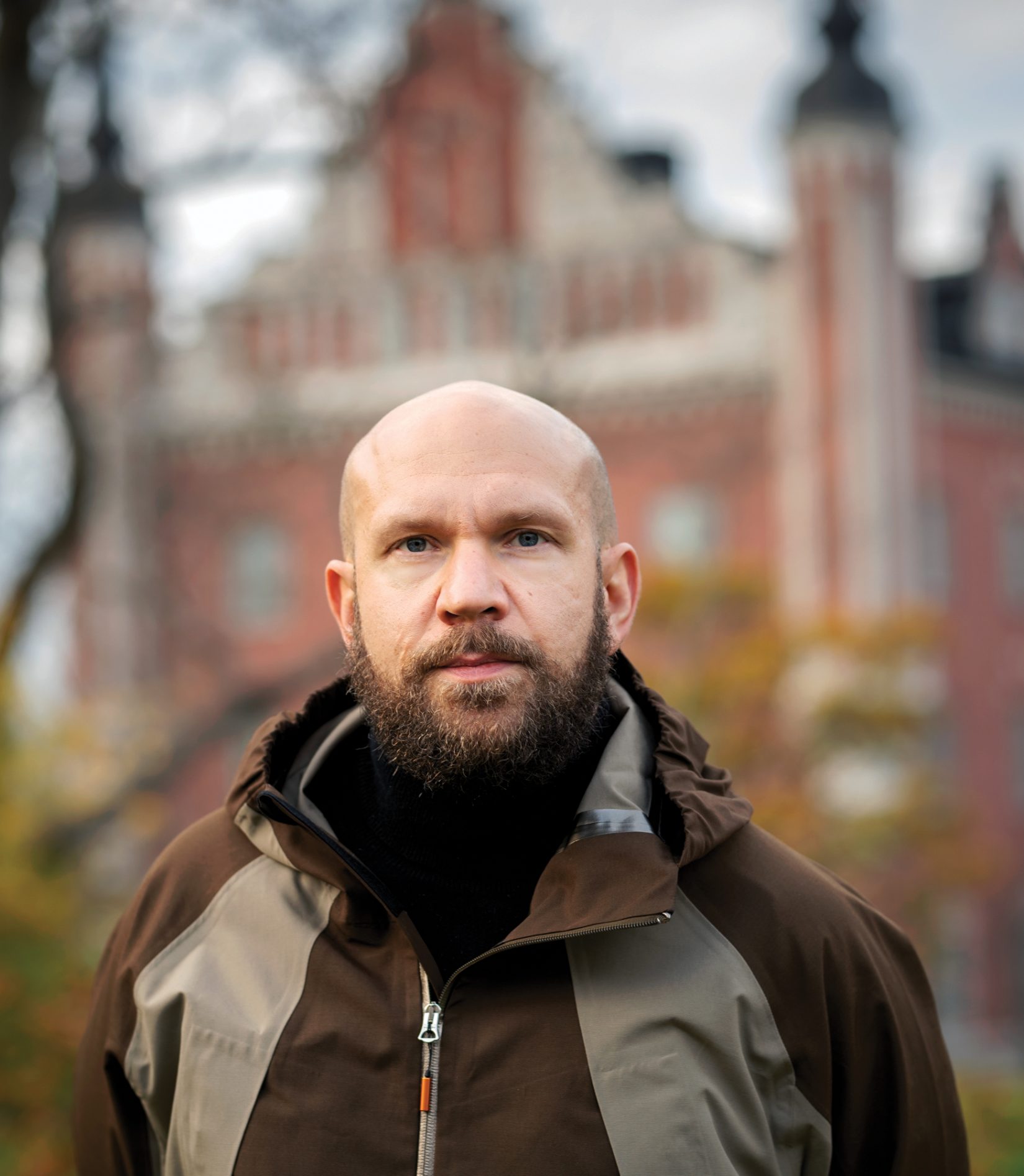 Porträttbild på Ilja Karilampi framför en byggnad en novemberdag.