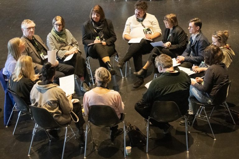 En grupp människor sitter i en ring och pratar