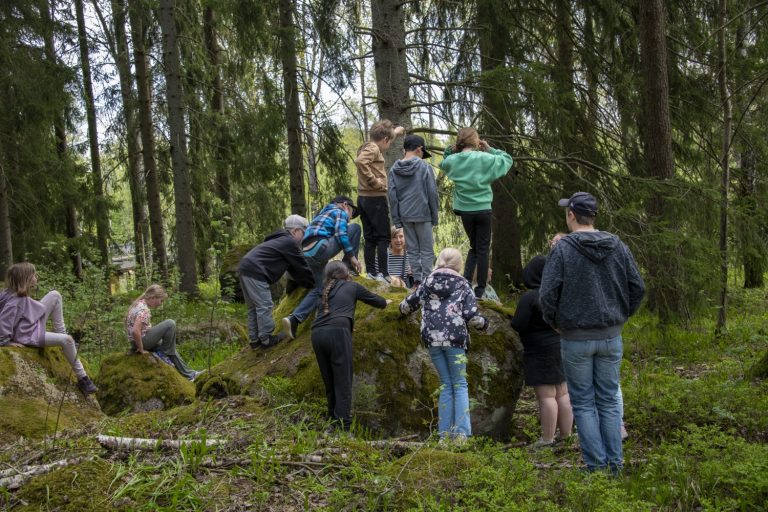 barn samlade runt stor sten i skogen