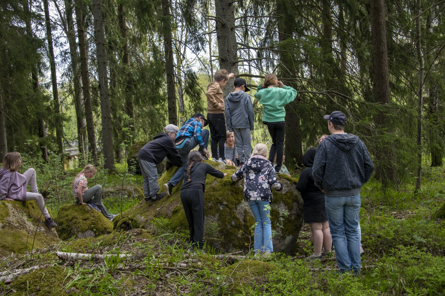 barn samlade runt stor sten i skogen