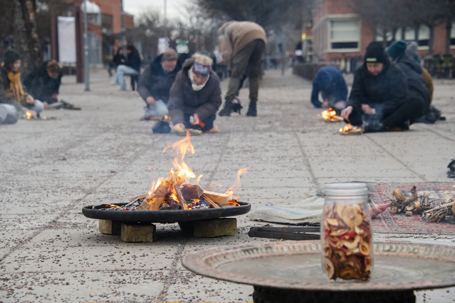 Personer som sitter på marken vi en eld