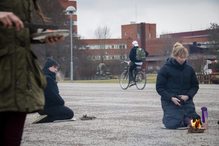 Två personer som sitter på marken vi en eld