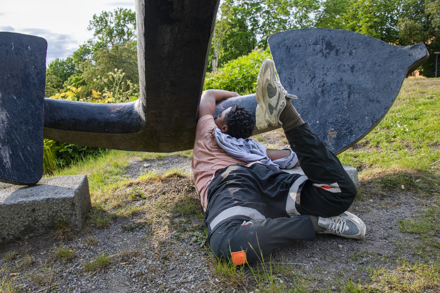 En man som ligger på marken bredvid en skulptur.