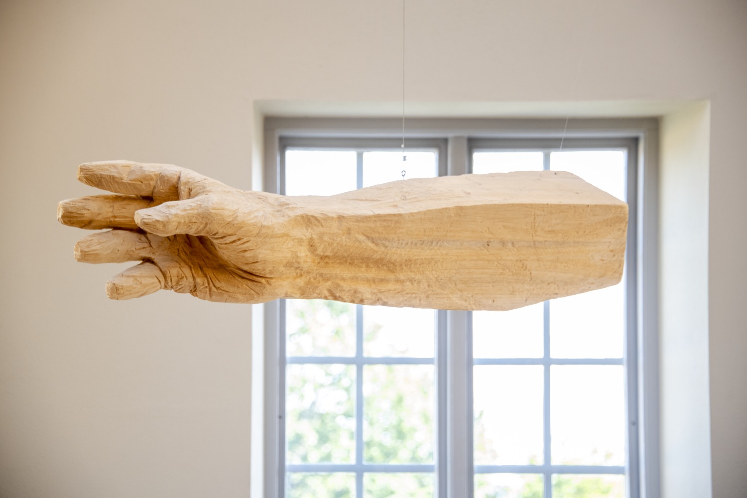 En träskulptur av en hand som håller i ett fönster.