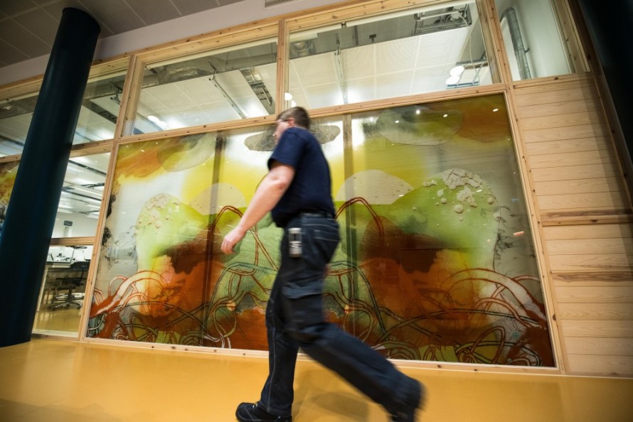 A man walking by a painted glass wall.