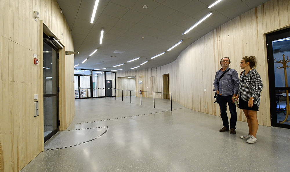 Two people standing in the corridor, listening.