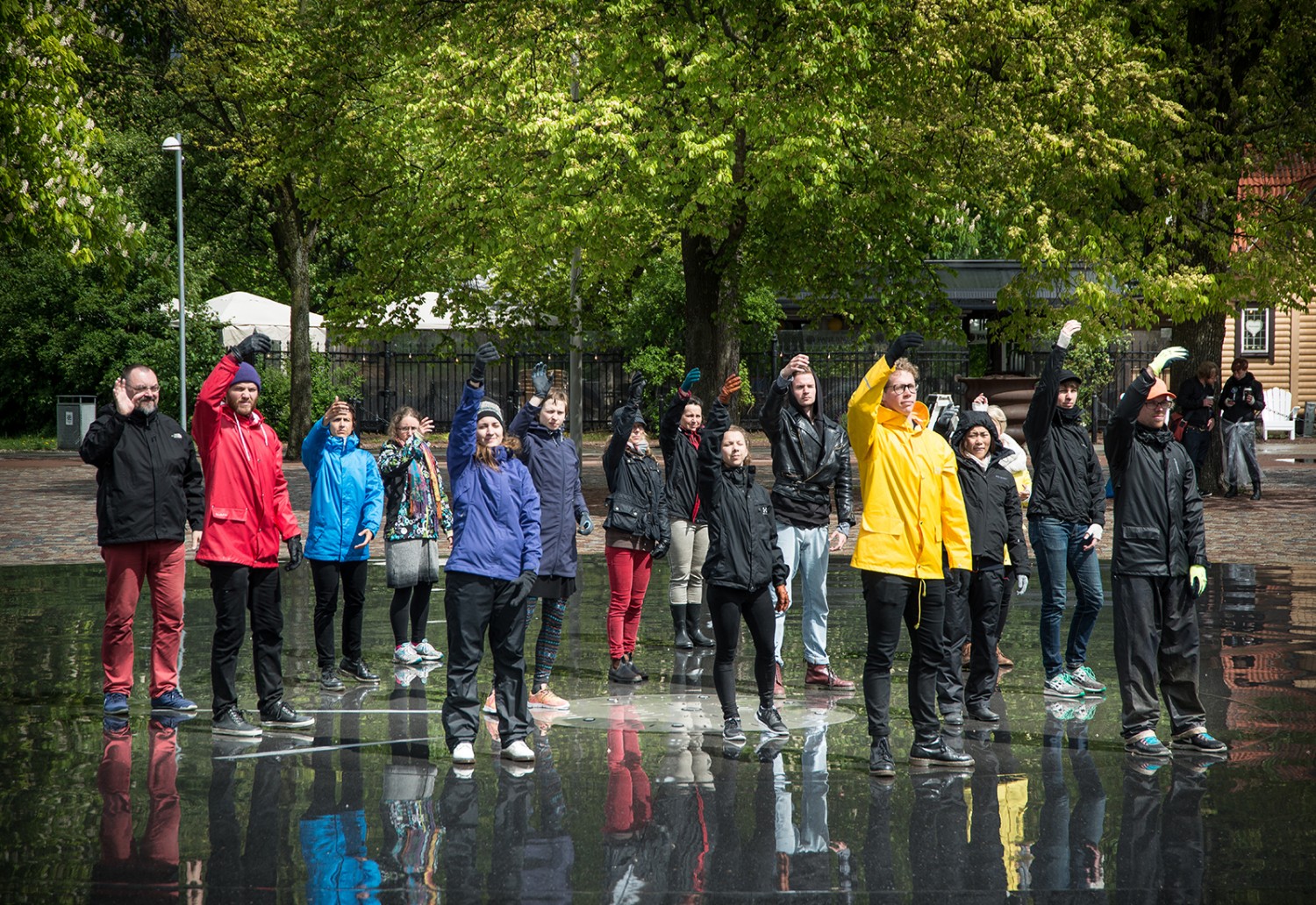 A group of peole in raincoats with their right arm raised.