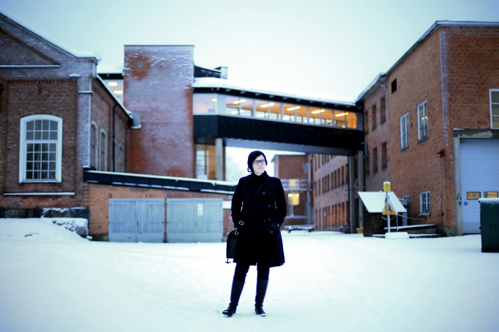 Artist Sara Jordenö in front of a factory.