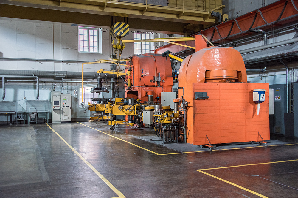 Inside a factory, with a big, orange, machine.