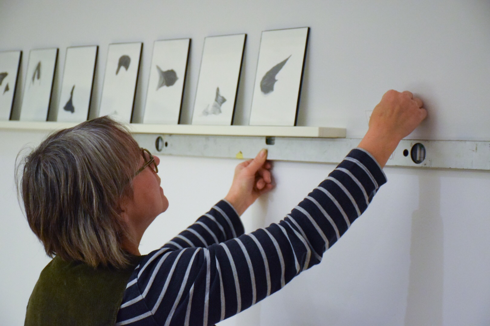 An artcurator measures the space on the wall.