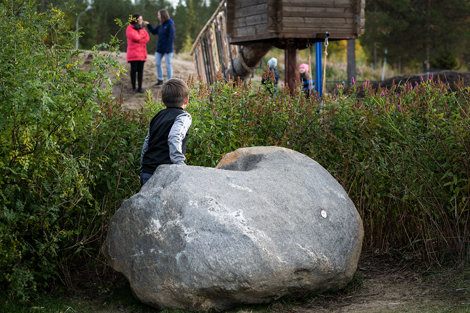 Small boy on a stone in front of a kindergarten.