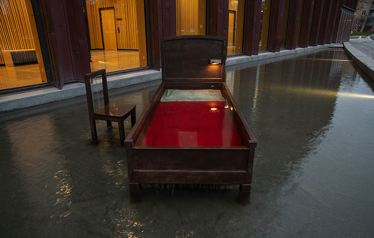 A bronze chair next to a bronze bed standing in water.