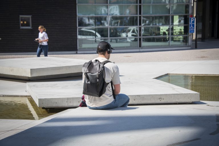 En person sitter på betongplatta. i Bakgrunder finns fler plattor och vatten.