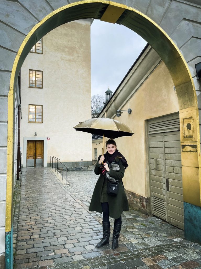 Maria W Horns står under verket Eter med ett paraply