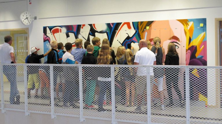 En stor grupp ungdomar trängs framför sina graffitimålade skåp, i färd med att låsa upp dem. Pärra Andreasson, Vad Vi Vill.