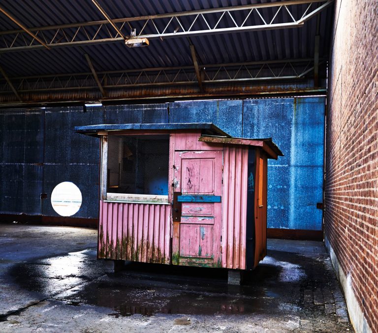 Slitet duvslag av trä, står i en byggnad av tegel och korrugerad plåt. Simon Starling, Loft Lift.