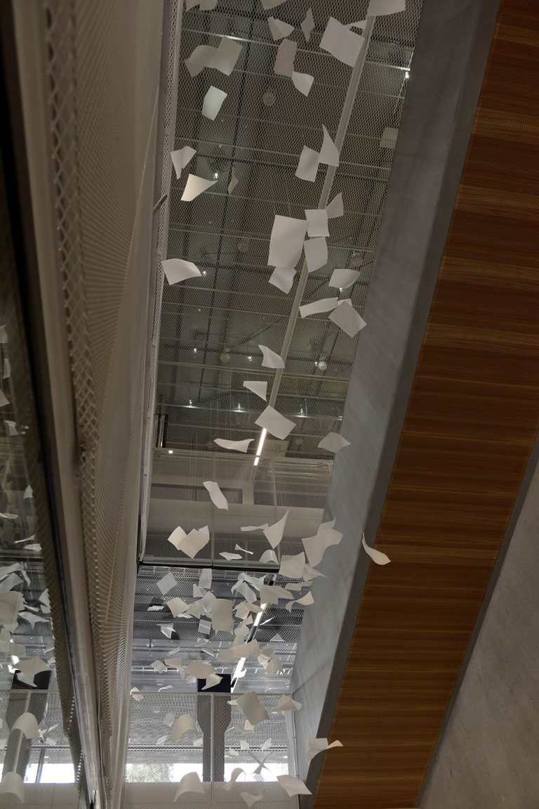 Virvlande pappersark i luften bredvid trappan. Gabriel Lester, Twirl, 2013