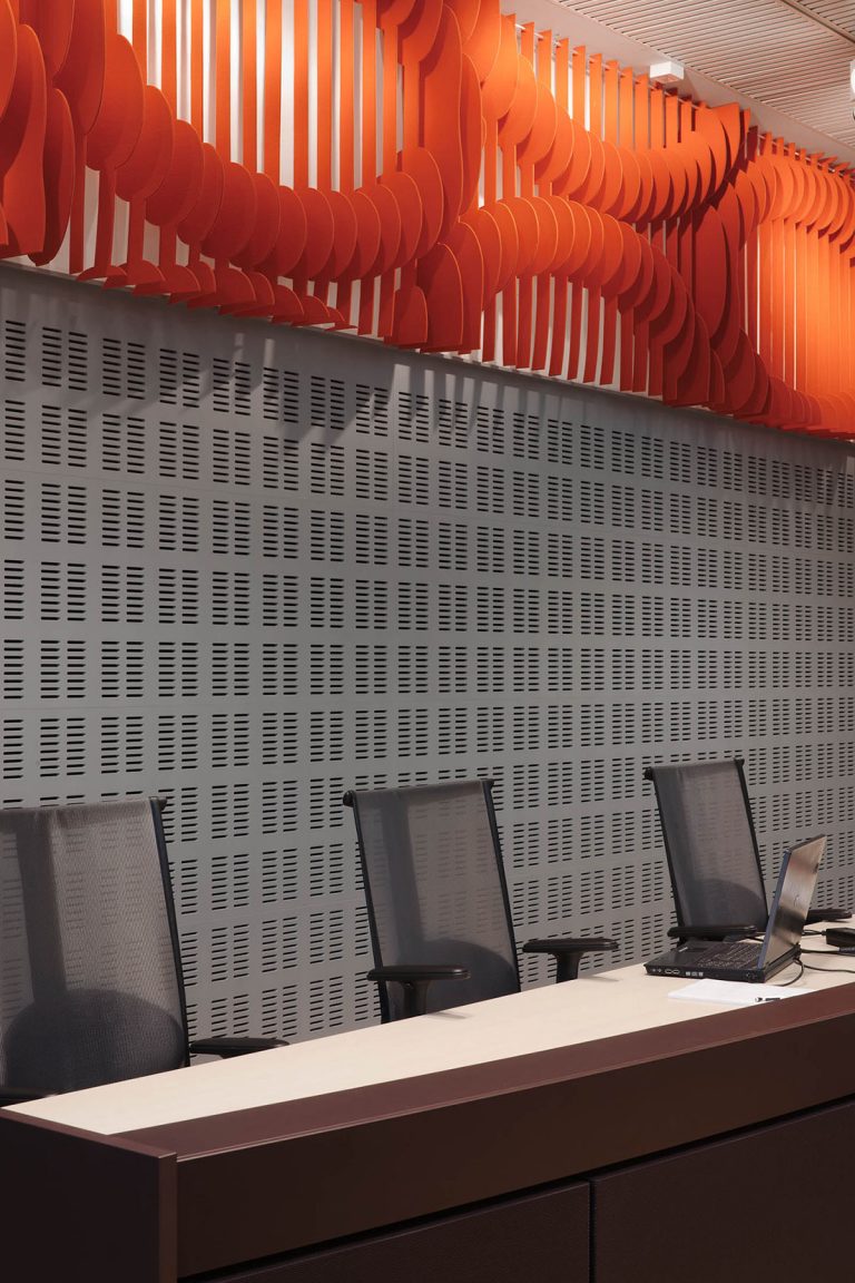 Panel på väggen ovanför domarbordet. Orangefärgad med utskurna cirkelmönster. May Bente Aronsen, Lyssnande vägg