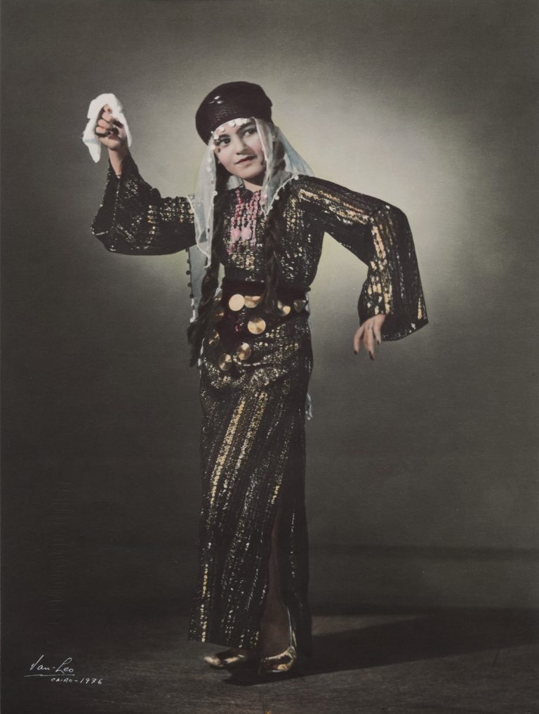 En kvinna i klänning och huvudbonad dansar med en näsduk