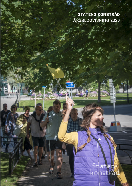 Framsida på årsredovisningen 2020. En kvinna i lila väsr leder en grupp människor genom en park. Hon håller i en liten gul flagga.