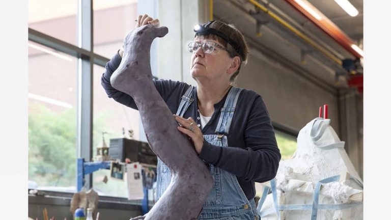 En kvinna skulpterar ett ben.