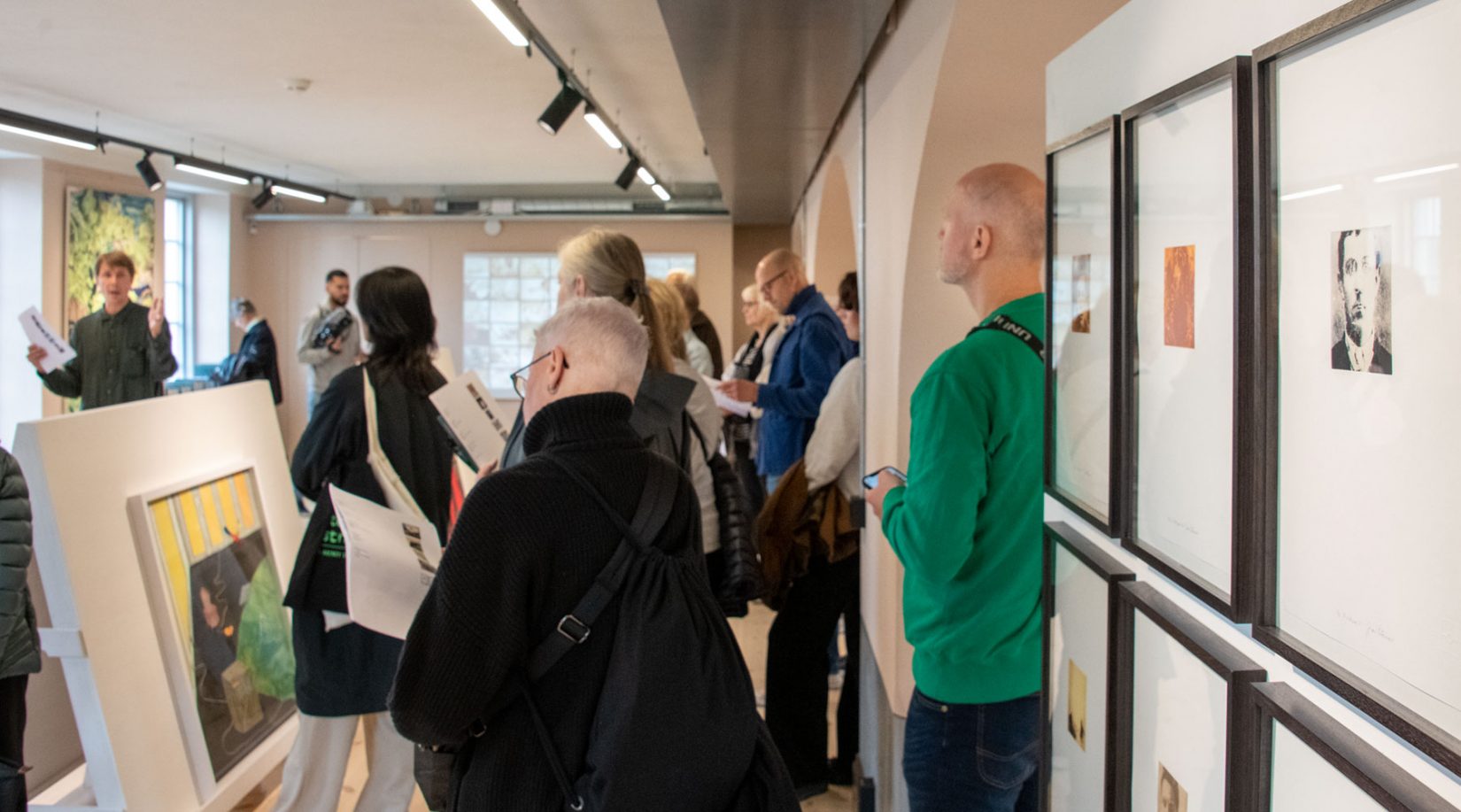 En grupp människor lyssnar på en curator i ett utställningrum