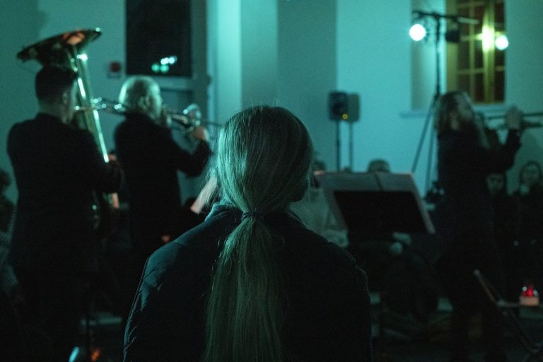 Bild på musiker och publik i ett mörkt rum